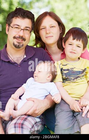 Glückliche Familie mit kind und Baby sitzt im Freien Foto Stock