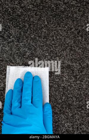 Persona che indossa guanti pulizia granito piano di lavoro da cucina con un panno antibatterico. Batteri di uccisione e concetto di germi Foto Stock