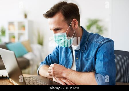 Freelancer che lavora a casa e indossa la maschera facciale Foto Stock