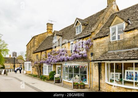 Negozi, stile locale e glicine in fiore in High Street, Broadway, Worcestershire, un bellissimo villaggio nelle Cotswolds, Inghilterra sud-occidentale Foto Stock