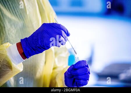 Dordrecht, Paesi Bassi. 21 Apr 2020. Un infermiere si prepara a fare un test COVID-19 Coronavirus alle persone in un'auto in un percorso attraverso il centro di test.il sistema sanitario olandese esamina le persone con lamentele sul coronavirus in un viaggio attraverso il centro di test COVID-19 Coronavirus allestito in GD Dordrecht, Il test viene eseguito prelevando un campione con tamponi di cotone all'interno del naso e almeno 140 persone vengono testate al giorno. Credit: SOPA Images Limited/Alamy Live News Foto Stock