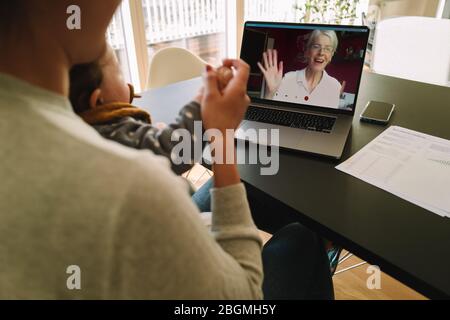 Donna con la figlia che ha videochiamata con la madre. Donna che si connette con la madre durante una videochiamata mentre si è a casa. Foto Stock