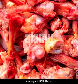 Molte ossa di pollo sguingiate crude nel mucchio giacciono sul tavolo. Mangiare persone povere o mangiare per i cani. Messa a fuoco selettiva. Quadrato. Primo piano. Ligh naturale Foto Stock