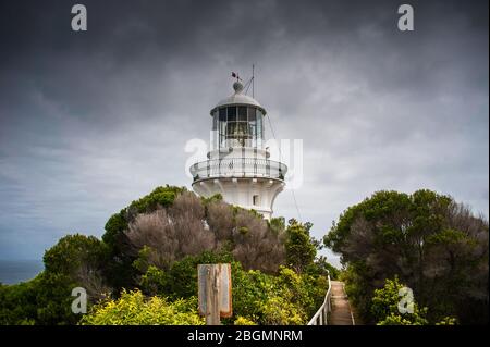 Sugarloaf Point lighthouse a Seal Rocks, Myall Lakes National Park, NSW, Australia. Faro sulla struttura collina coperta e grigio cielo cloud Foto Stock