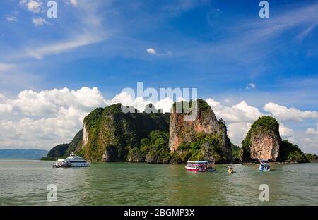 Il carsico calcareo sorge fuori dal Mare delle Andamane, nella Baia di Phang Nga, in Thailandia. Bella stagione, cielo blu nuvoloso e isola tropicale con barche da tour Foto Stock