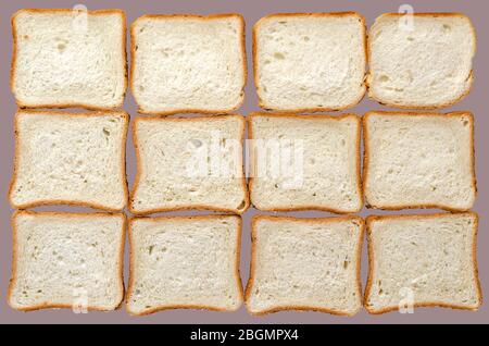 Pane tostato sfondo. Dodici fette di pane affettato su sfondo grigio. Fette rettangolari di pane di grano. Vista dall'alto. Foto Stock