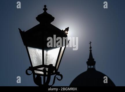 Potsdam, Germania. 22 aprile 2020. Il sole è dietro la replica di una storica lampada da strada di fronte alla sagoma della cupola della chiesa di San Nicola. Credit: Soeren Stache/dpa-Zentralbild/ZB/dpa/Alamy Live News Foto Stock