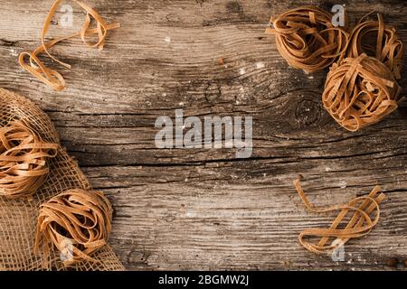 pasta su un tavolo di legno - pasta fatta in casa adagiata su un tavolo di legno rustico. Foto Stock