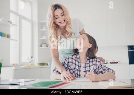 Ritratto di due persone madre casalinga positivo aiuto quarantena distanza educazione ragazza capretto scrivere nota libro guardare tavolo in casa cucina al chiuso Foto Stock