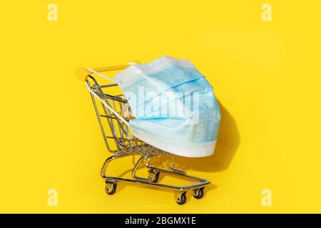 Carrello con maschera protettiva su sfondo giallo. Foto Stock