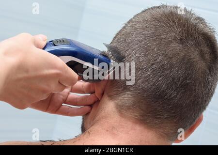 Il parrucchiere leviga e accorcia i capelli sulla testa dell'uomo in bagno Foto Stock