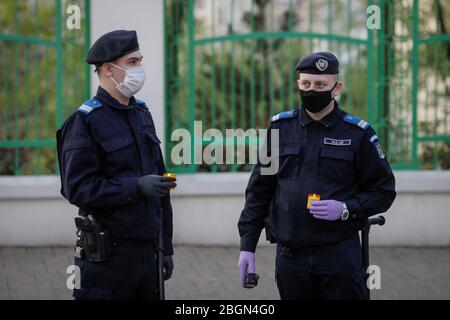 Bucarest, Romania - 18 aprile 2020: Gendarmi rumene con maschere chirurgiche a causa della pandemia covid-19 prendere la Santa luce durante l'Easte ortodossa Foto Stock