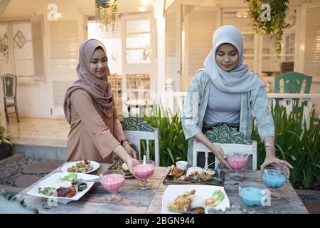 bella donna musulmana che prepara la tabella per rompere il digiuno con l'amico e la famiglia su ramadan Foto Stock