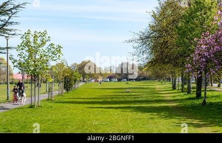 Leith, Edimburgo, Scozia, Regno Unito. 22 aprile 2020. Covid-19 Lockdown: La gente esercita sui collegamenti di Leith nel sole di primavera durante la pandemia di Coronavirus. Una famiglia a cavallo biciclette attraverso il parco Foto Stock