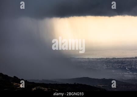 Vista ravvicinata della pioggia pesante sopra Pafo (o Paphos) come visto dalle alture di Akamas, Cipro Foto Stock