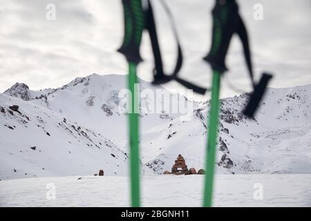 Alte montagne innevate e pali trekking in primo piano. Turismo e concetto di trekking Foto Stock