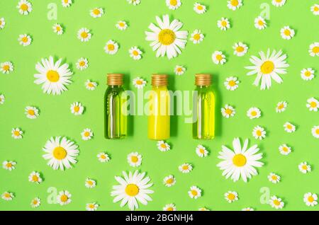 Piatto di laici piccolo mockup bottiglie con spa prodotti cosmetici su sfondo verde con freschi Fiori di camomilla. Le donne di bellezza e un salone di bellezza cosmetici Foto Stock