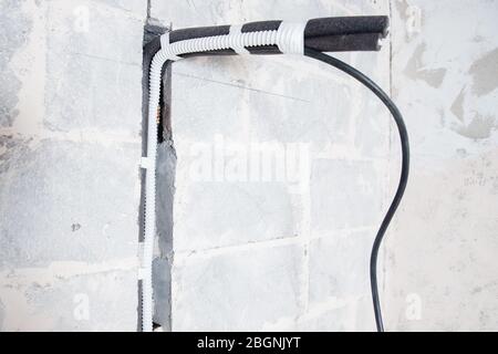 Installation of pipe channel for connecting air conditioner in concrete wall Foto Stock