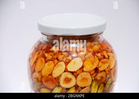 Un vaso di miele greco e noci (pistacchi, arachidi, nocciole, pinoli, mandorle, noci) in luce naturale Foto Stock