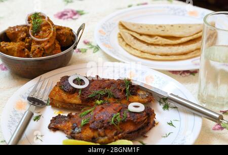 Gustoso e piccante pesce fritto, pesce curry e roti o pane dalla cucina indiana. Foto Stock