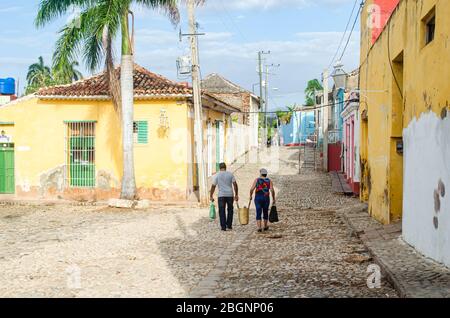 Scena mattutina per le strade di Trinidad a Cuba. Una coppia sta camminando con i cestini tradizionali dello shopping della paglia Foto Stock