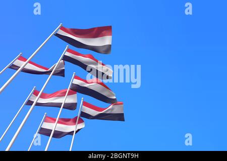 Le bandiere dello Yemen che ondeggiavano nel vento contro un cielo blu. Rendering 3D Foto Stock