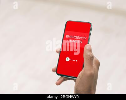 Uomo che tiene uno smartphone con numero di emergenza Foto Stock