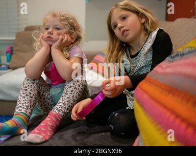 3 aprile 2020 due giovani sorelle annoiano a casa guardando la televisione. Hanno 4 e 2 anni. Preso durante il blocco del coronavirus. Londra, Regno Unito Foto Stock