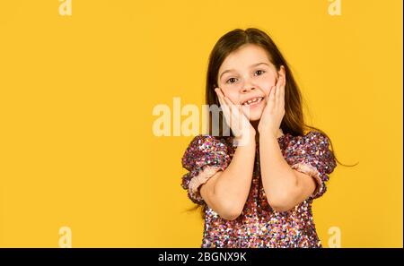 Faccia preziosa. Bambino tira le guance in su nell'affetto. Ragazza sorriso carino su sfondo giallo. Concetto di infanzia e felicità. Capretto con spazio allegro copia faccia. Felice giorno per i bambini. Infanzia felice. Foto Stock