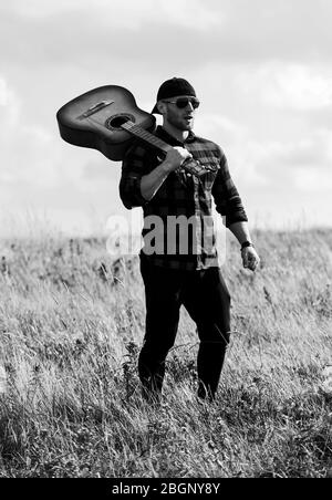 Uniti con la natura. La vacanza estiva. Trasognata wanderer. Atmosfera pacifica. Escursionismo canzone. Un musicista in cerca di ispirazione. Ispirando la natura. Uomo bello con la chitarra a contemplare la natura. In cerca di muse. Foto Stock