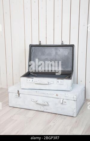 due antiche valigie bianche contro una parete di legno bianco Foto Stock
