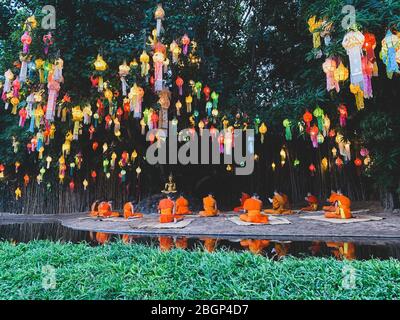 I monaci buddisti si siedono meditating sotto la luce della bella lanterna di carta ogni anno al tempio di Wat Pan Tao Foto Stock