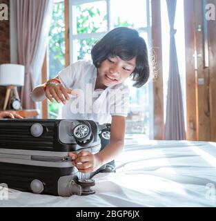 la ragazza asiatica prepara i vestiti e le valigie per essere portata quando mudik andare al villaggio Foto Stock