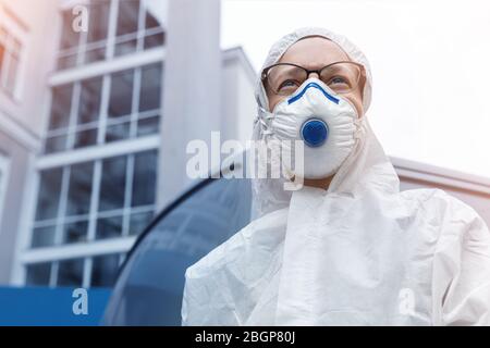 Ritratto di stanco esausto medico femmina, scienziato o infermiere che indossa maschera facciale e biologico Hazmat ppe tuta cercando in preda con ansia Foto Stock