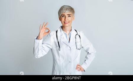 Medico donna che mostra ok segno con la mano Foto Stock