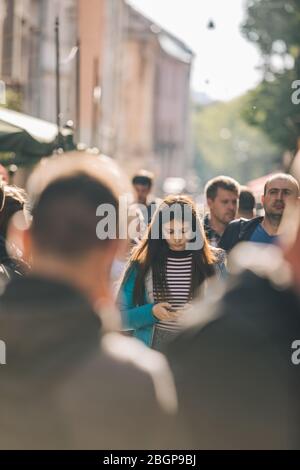 Lviv, Ucraina - 11 maggio 2019: Giovane donna in folla in città strada utilizzando il telefono Foto Stock