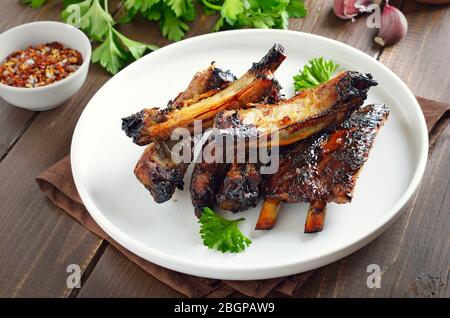 Costolette di maiale alla griglia su piatto bianco. Gustosa carne barbecue Foto Stock