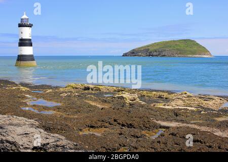 Penmon Point Faro con Puffin Island in lontananza, Anglesey, Galles, Regno Unito Foto Stock