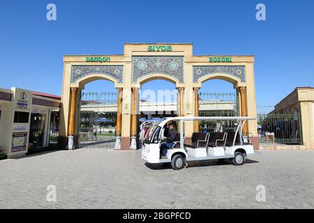 Archi all'ingresso del Bazaar Siyob (Siab Bazar) e auto elettrica, utilizzati principalmente dai turisti a Samarkand, Uzbekistan. Foto Stock