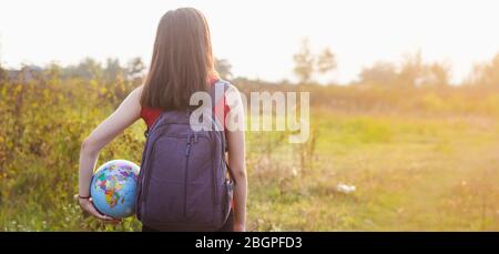 ragazza con backback che tiene il globo in luce del tramonto sfondo Foto Stock