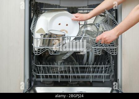 Piatti lavati male in lavastoviglie. Lavastoviglie integrata con piastre bianche davanti a vew e triste emozione su piastra. Macchina lavastoviglie rotta concetto Foto Stock