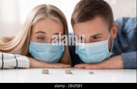 Uomo e donna tristi in maschere protettive contando gli ultimi soldi Foto Stock