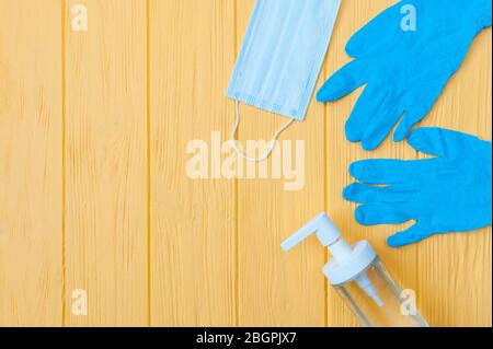 Flacone igienizzante per mani, maschera respiratoria facciale e guanti su sfondo giallo. Richiedere la disinfezione delle mani. Stop concetto di coronavirus. Utilizzo Foto Stock