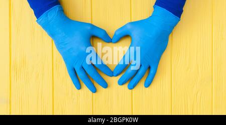 Guanti blu in nitrile. Mani di medica nei guanti blu in lattice sul banner giallo tavolo in legno Foto Stock