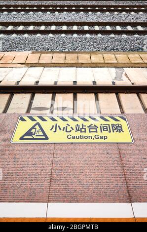 Avvertimento di distanza di attenzione in cinese e inglese alla stazione ferroviaria ad alta velocità a Kunming, Cina. Foto Stock