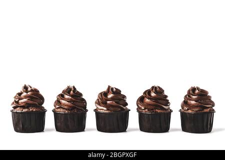 Deliziosi cupcake al cioccolato con scintille d'oro spruzzate sulla glassa di cioccolato allineati su sfondo bianco isolato. Mockup per il tuo design. Primo piano. Foto Stock