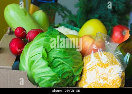 Scatola con frutta e verdura mele cavolo rafano olio zucchine, grits primo piano. Servizi di consegna di cibo durante la pandemia di coronavirus e sociale Foto Stock