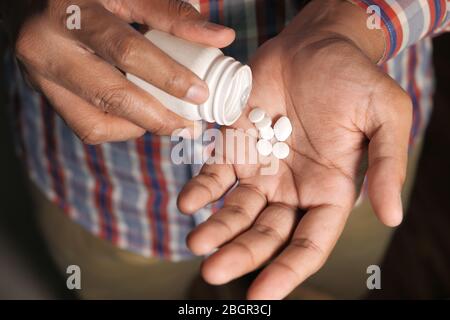 Versando le pillole dalla bottiglia bianca nel palmo Foto Stock