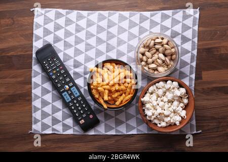 Una ciotola di patatine di popcorn, dado e telecomando TV, Foto Stock