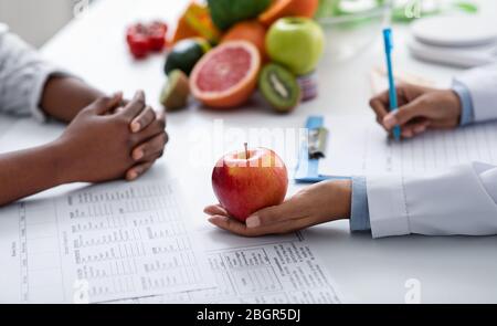 Primo piano del dietologo e del paziente passa sopra il posto di lavoro del medico Foto Stock